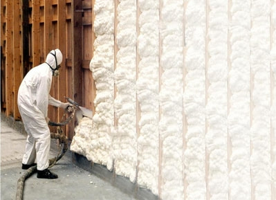 contractor spraying with foam a house wall